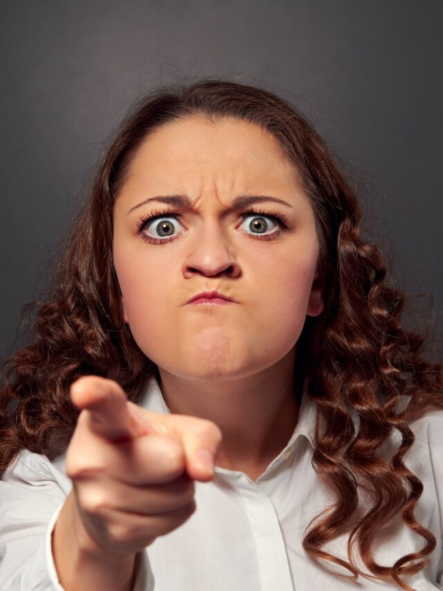 Angry,Young,Woman,Pointing,At,Camera,Over,Grey,Background