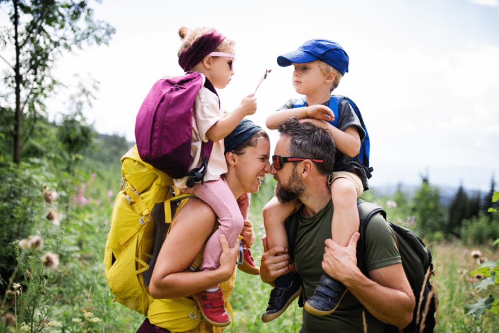 Family with small children hiking outdoors in summer nature.