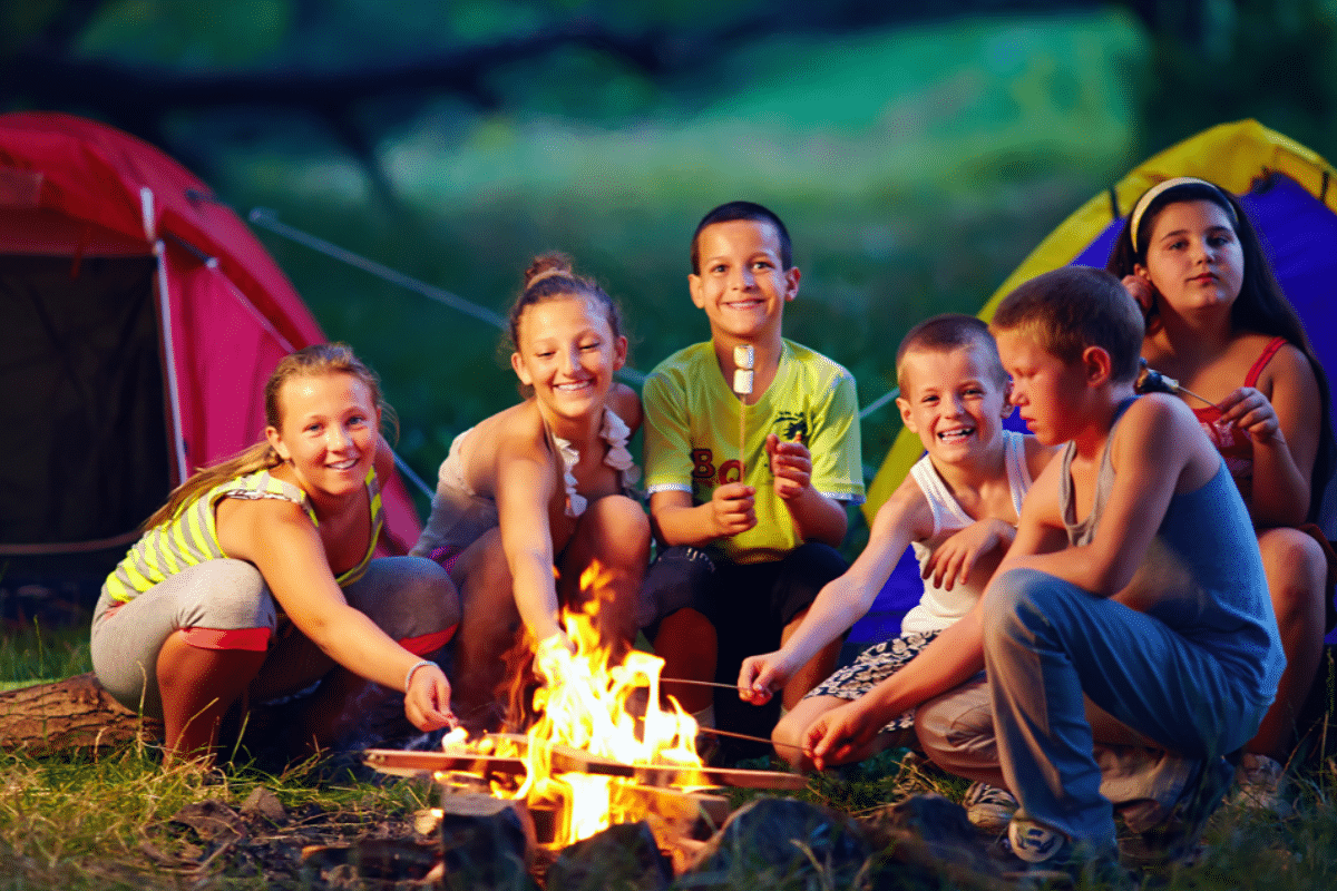 group of happy kids roasting marshmallows on campfire