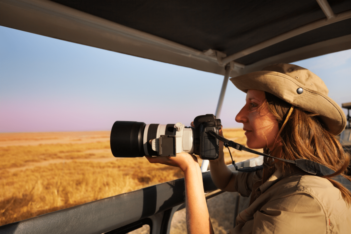 Woman taking photo aboard safari jeep at savannah